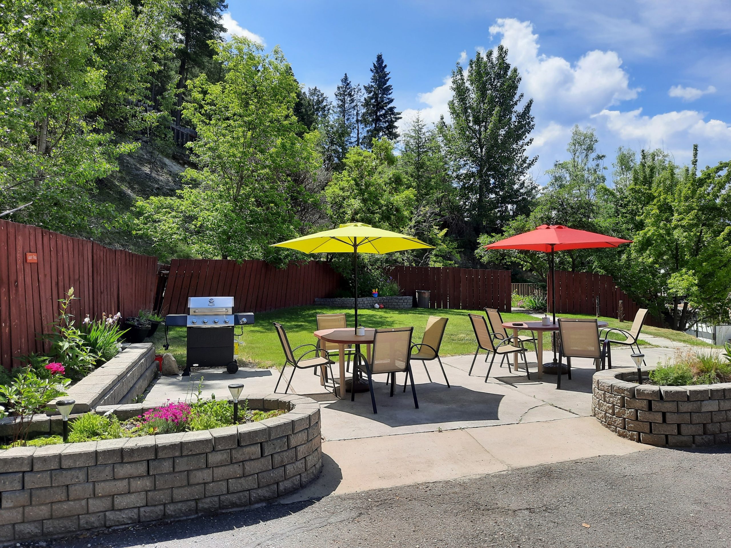 A patio with seating and tables with umbrellas for shade outside on a sunny day.