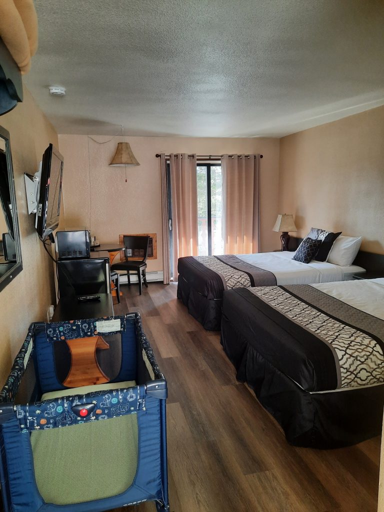 Motel room with two queen beds and an infant cot.