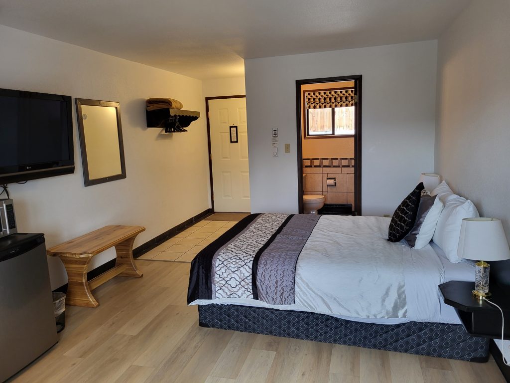 One queen size bed freshly made in a motel room.